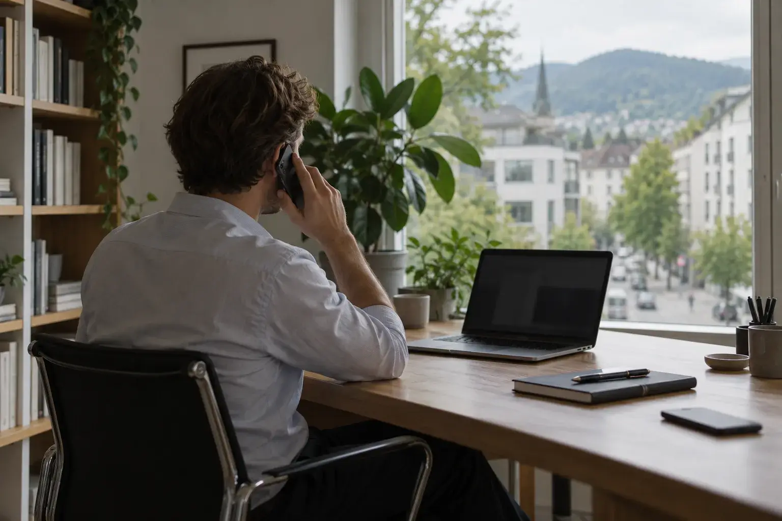 Un consultant au téléphone à son bureau, devant une fenêtre sur la ville.